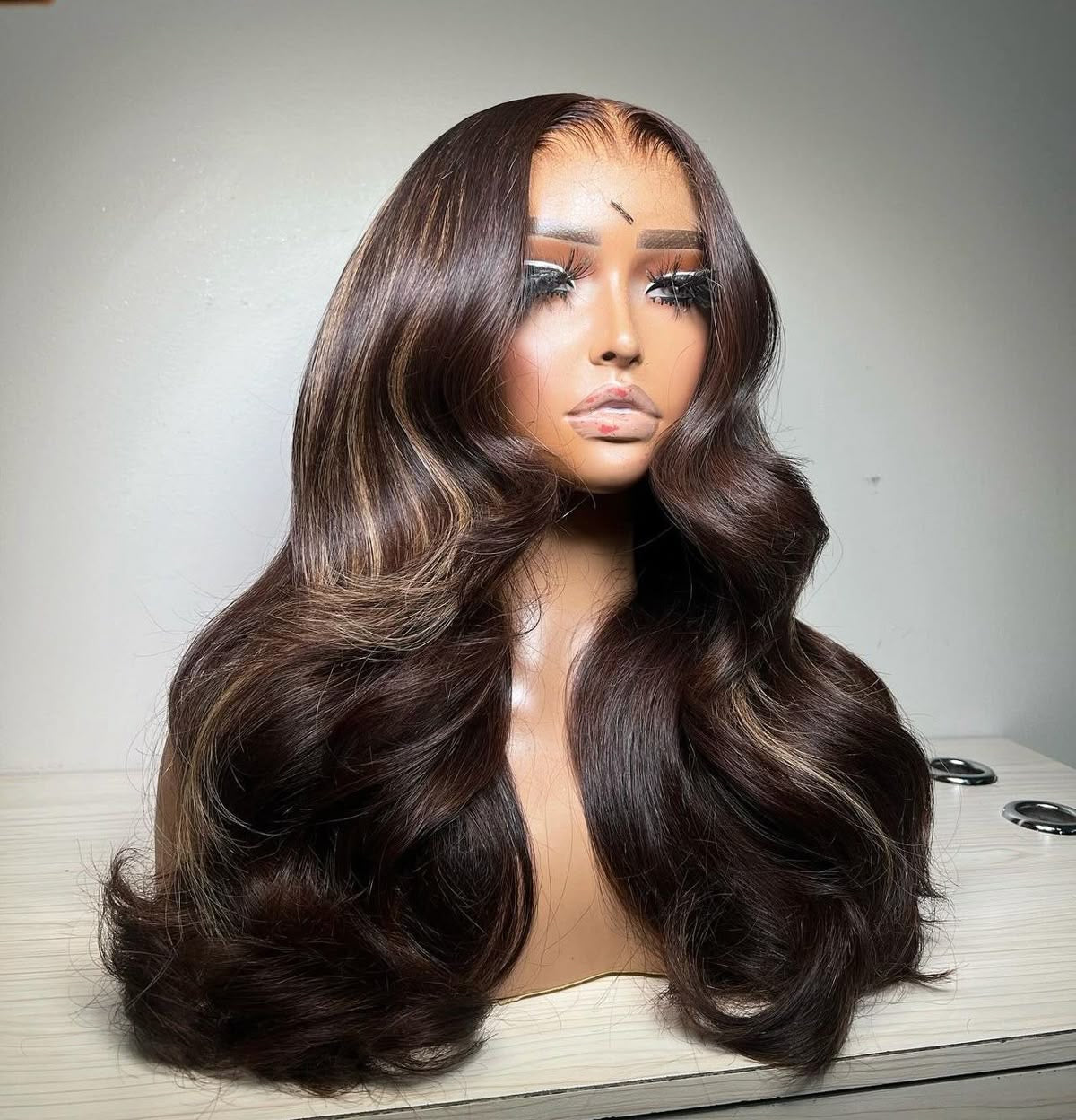 Long dark brown wig with large flowing curls displayed on a mannequin from an angle.
