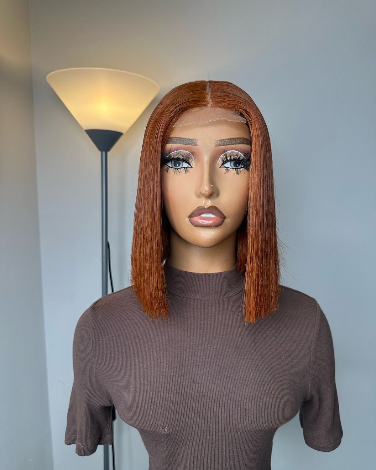 Copper-brown straight bob wig with a centre part on a mannequin, viewed from the front.